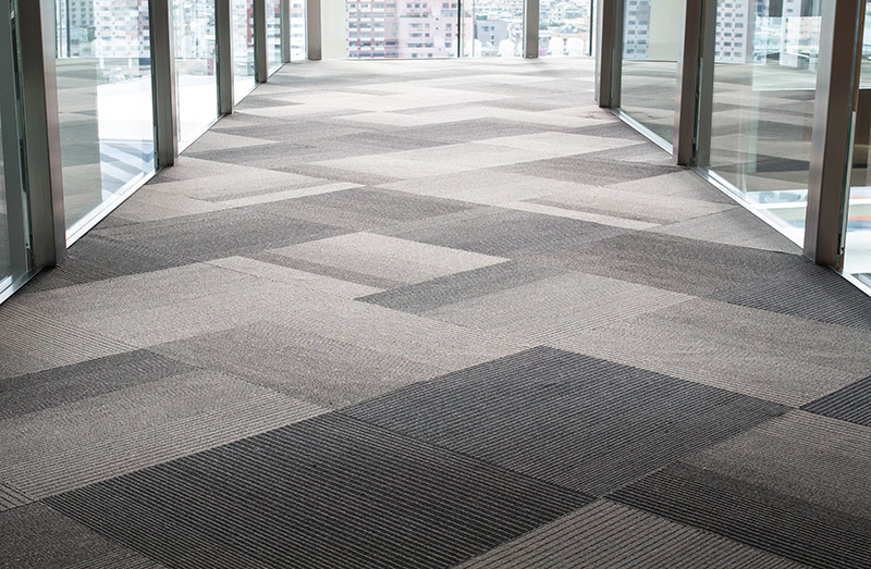 Modern office interior with a mix of dark grey and light grey carpet tiles, creating a stylish and professional flooring design.