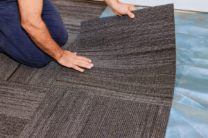 A man placing carpet tiles in an office